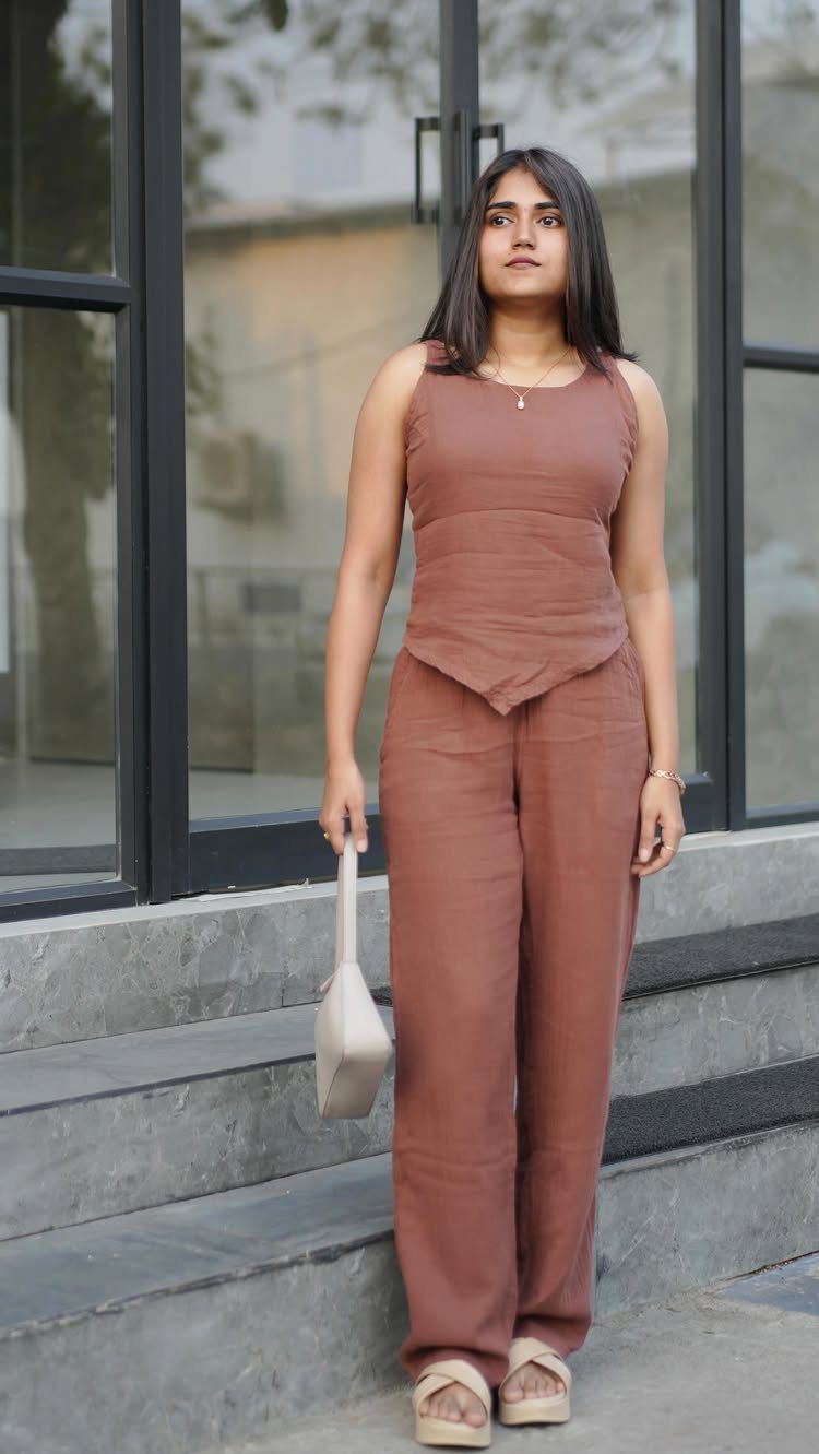 A young woman posing in a terracotta linen matching two-piece sleeveless top and wide-leg trousers.