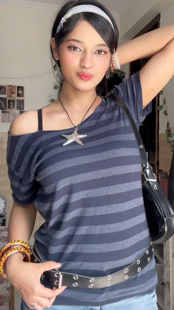 A young woman posing in a striped off-the-shoulder t-shirt and star necklace.