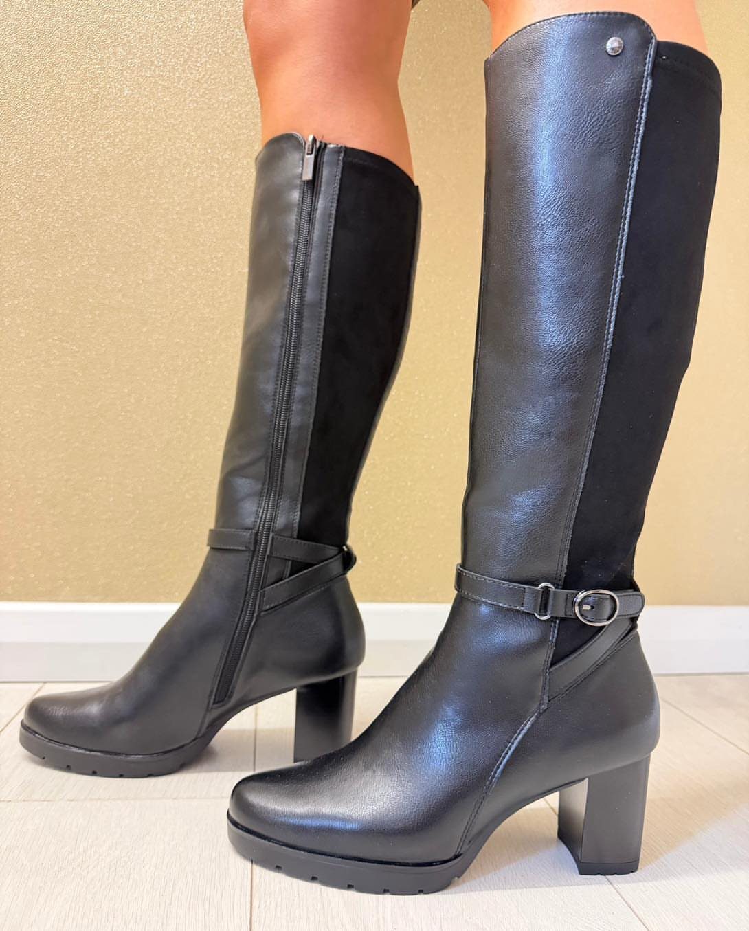 Black knee-high boots with leather and suede panels featuring a small ankle strap detail.