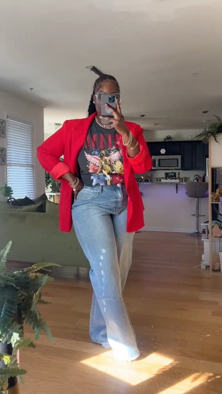 A person posing in light blue baggy jeans, a graphic tee, and a bright red blazer.