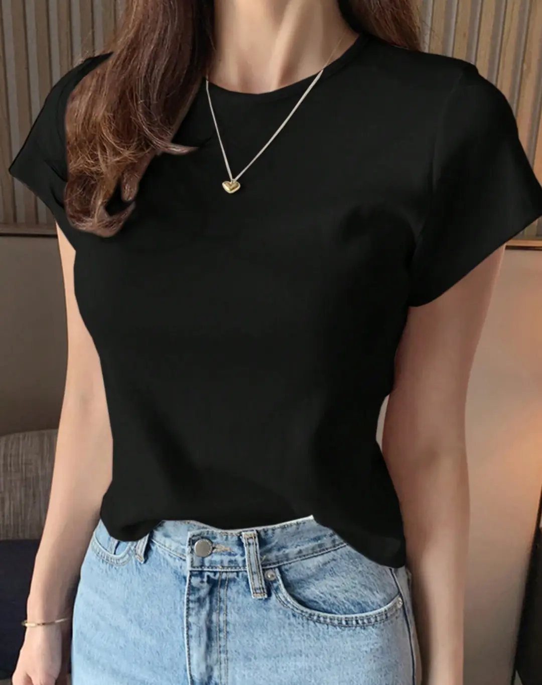 Woman wearing a black short-sleeved t-shirt and light blue denim jeans.