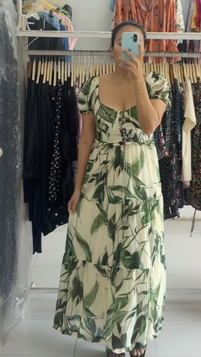 Woman in a cream and green tropical leaf print maxi dress taking a mirror selfie.
