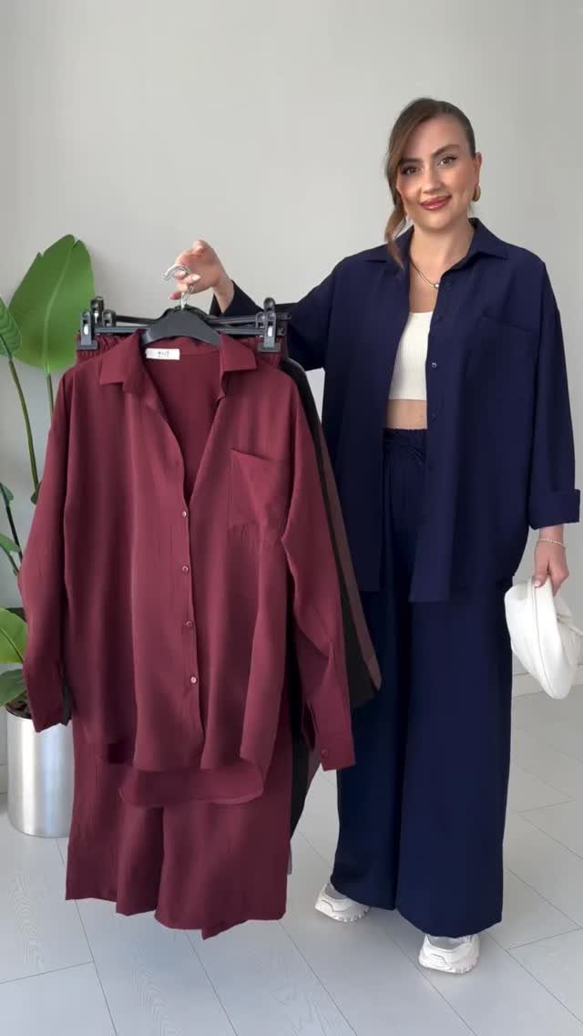 A woman holding a clothing rack displaying burgundy and navy blue matching loungewear sets.