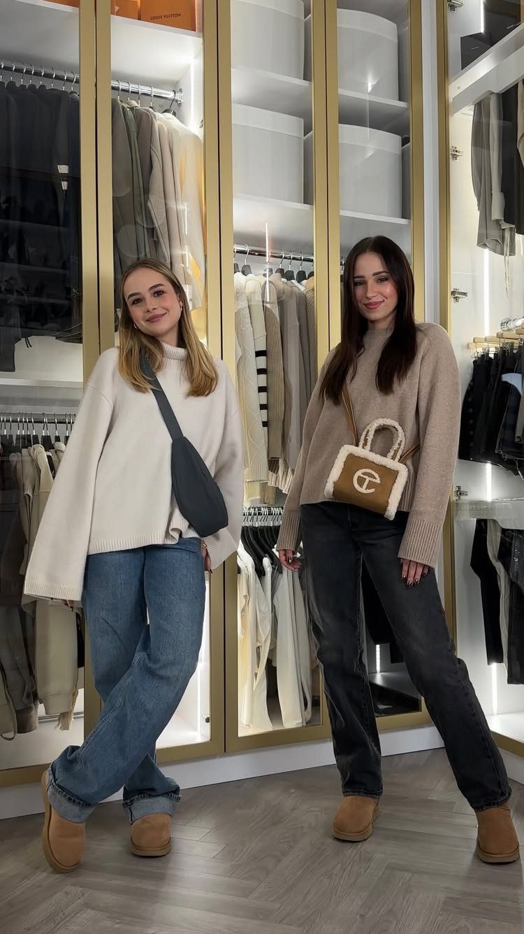 Two women posing in a modern walk-in closet wearing casual sweaters and jeans.