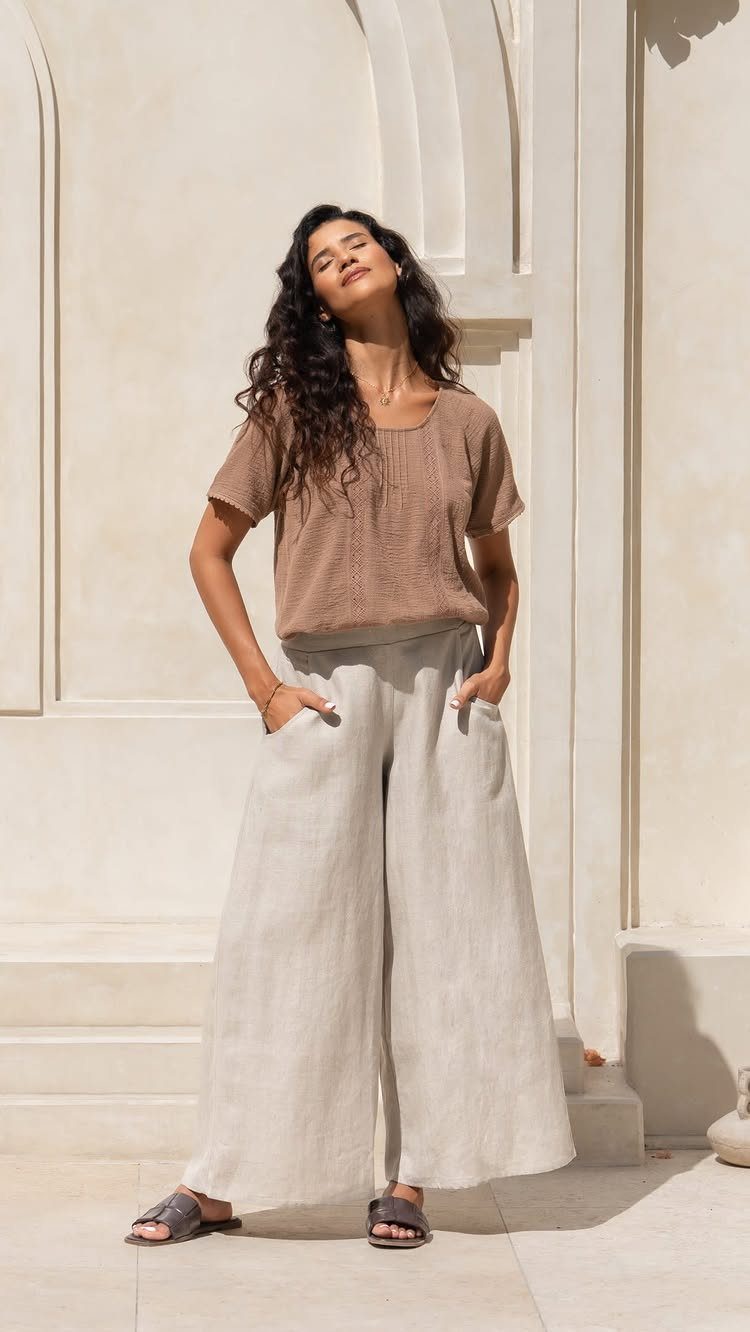Woman wearing a tan blouse and wide-leg beige linen pants standing outdoors.