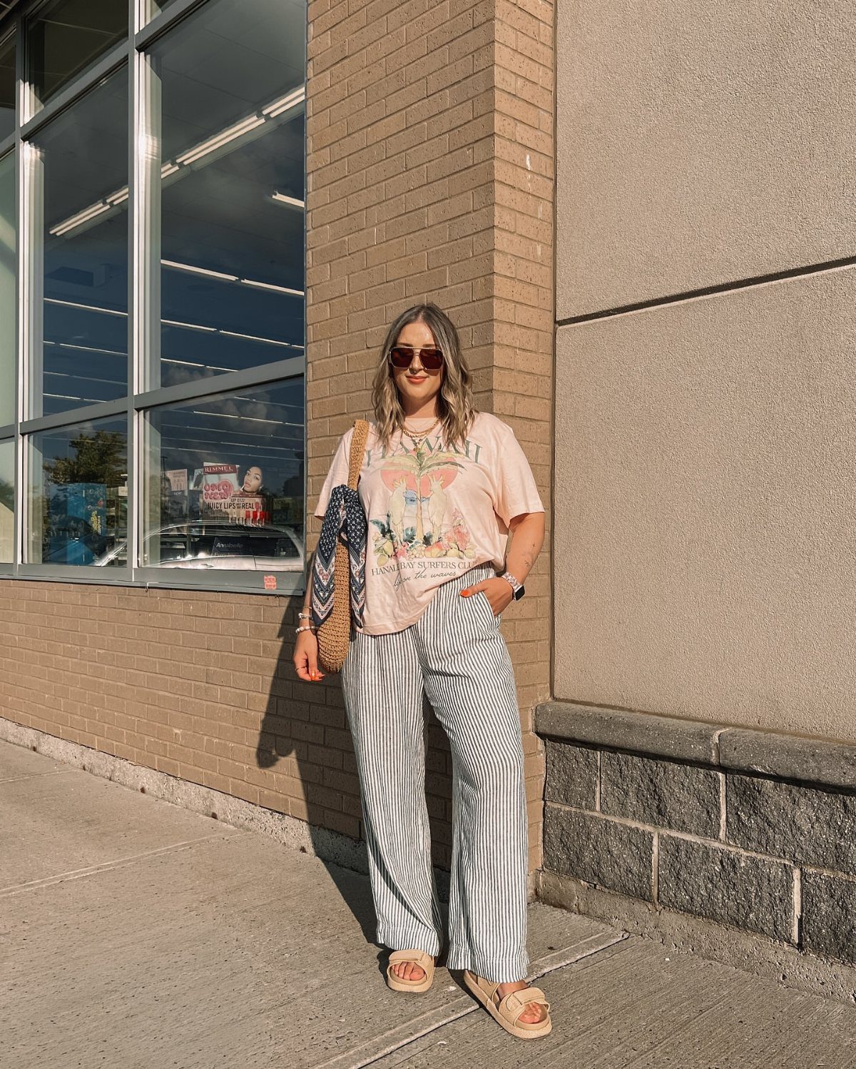 Woman wearing a peach graphic t-shirt and blue and white striped wide-leg pants.