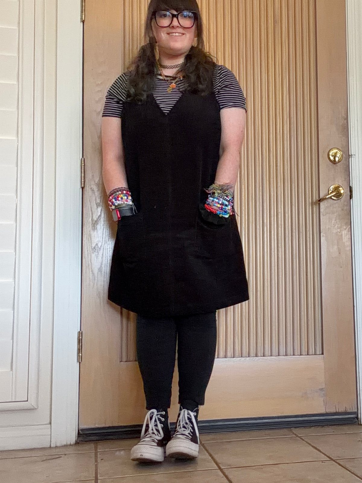 Woman wearing a black tunic, striped shirt, black leggings, and white high-top sneakers.