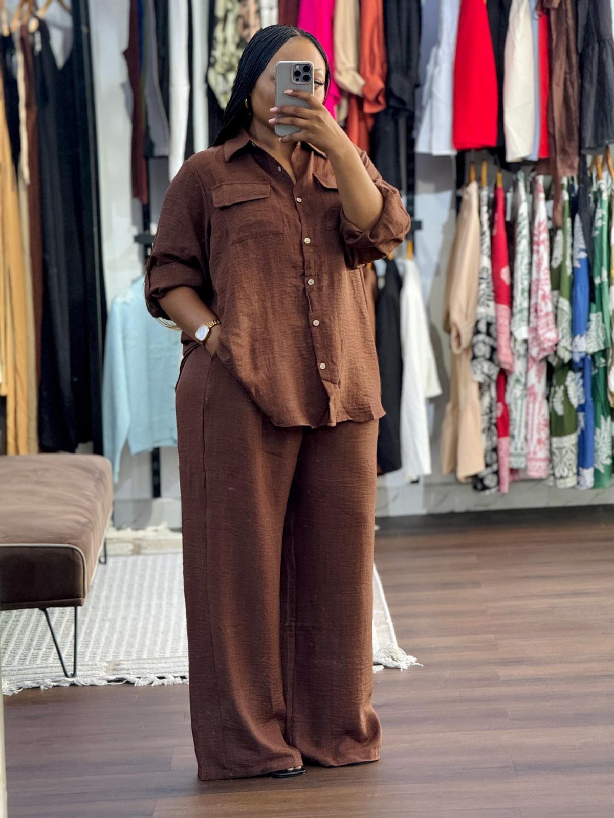A woman posing in a mirror wearing a matching brown button-down shirt and wide-leg trousers set.