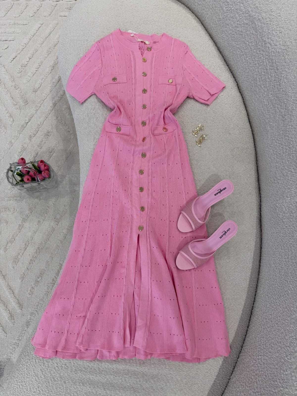 Pink knit midi dress with gold buttons laid flat with matching pink heels.