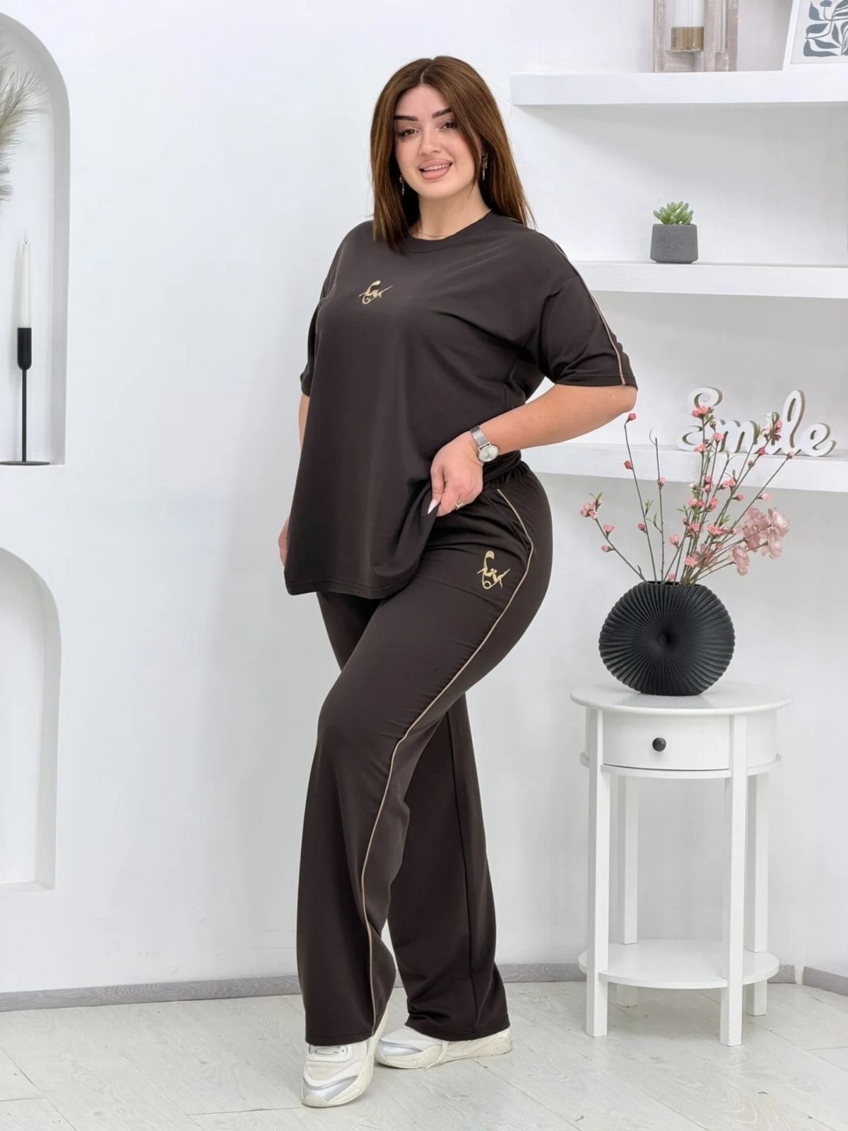 Woman in dark brown oversized t-shirt and matching wide-leg lounge pants standing indoors.
