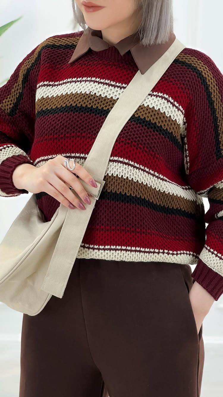 A person wearing a striped burgundy and cream chunky knit sweater with a brown collar.