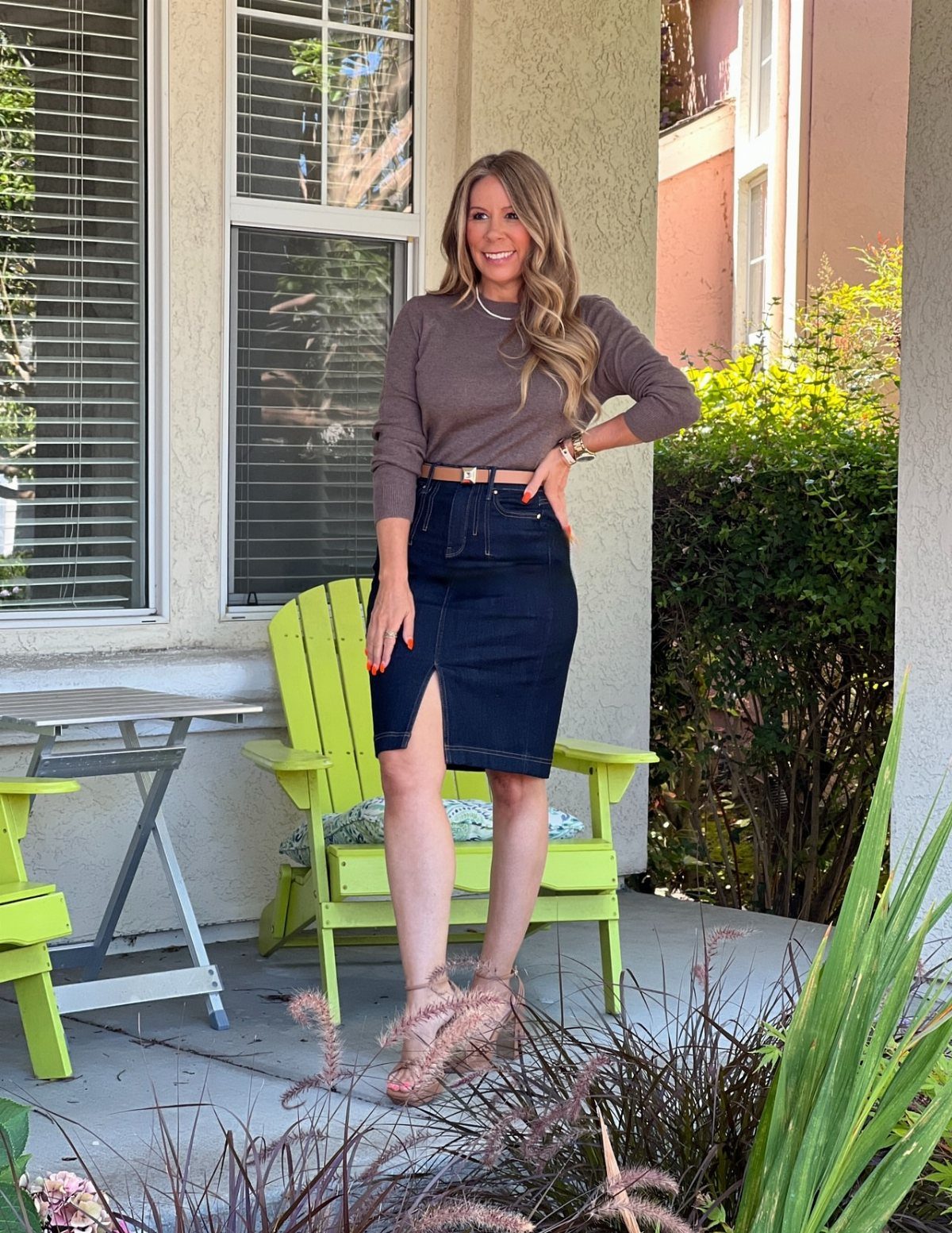 A woman wearing a brown top and a dark denim pencil skirt standing outdoors.