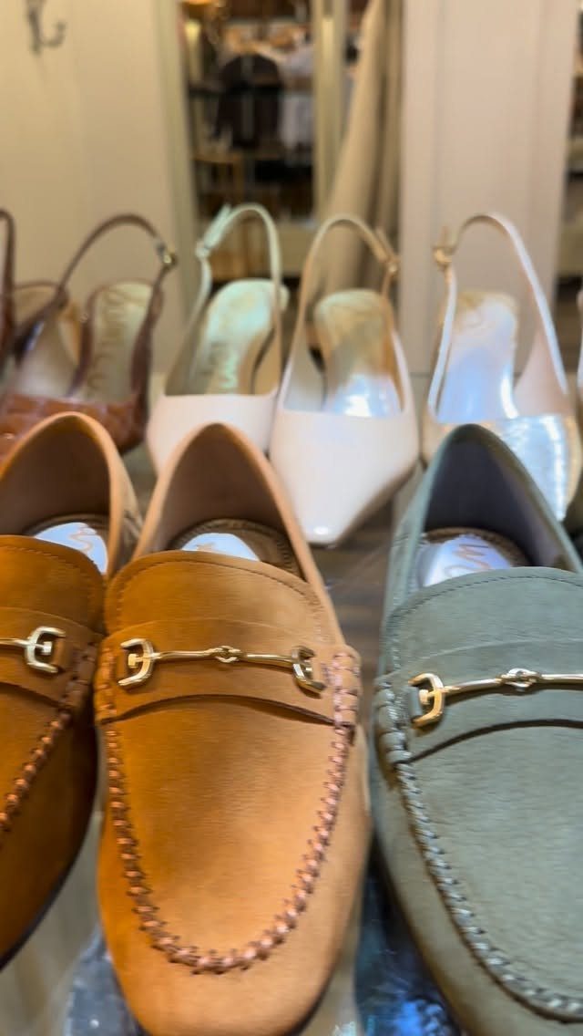 Tan and sage green suede loafers with gold hardware displayed on a retail shelf.