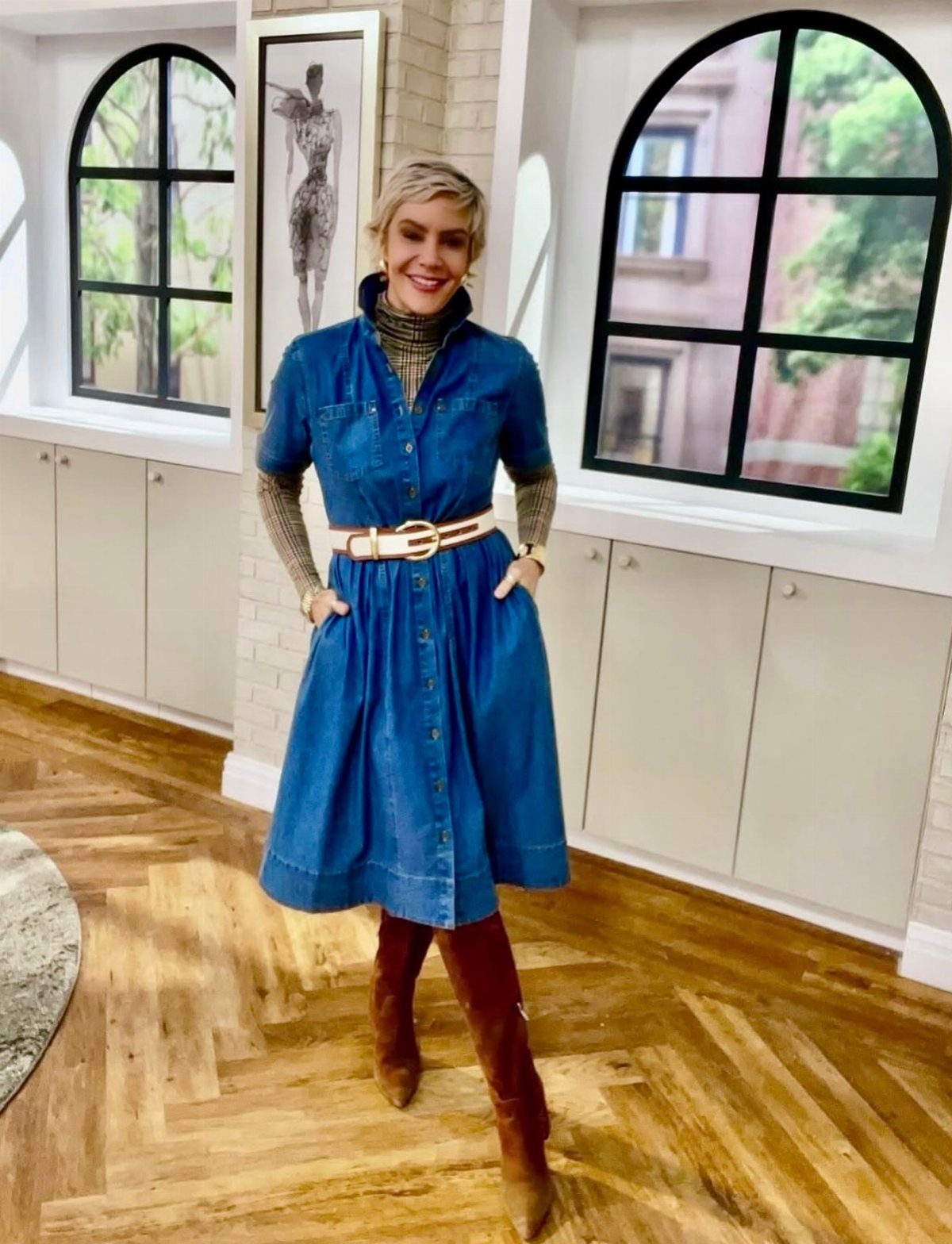 A woman wearing a blue denim midi dress, tan turtleneck, and brown suede boots.