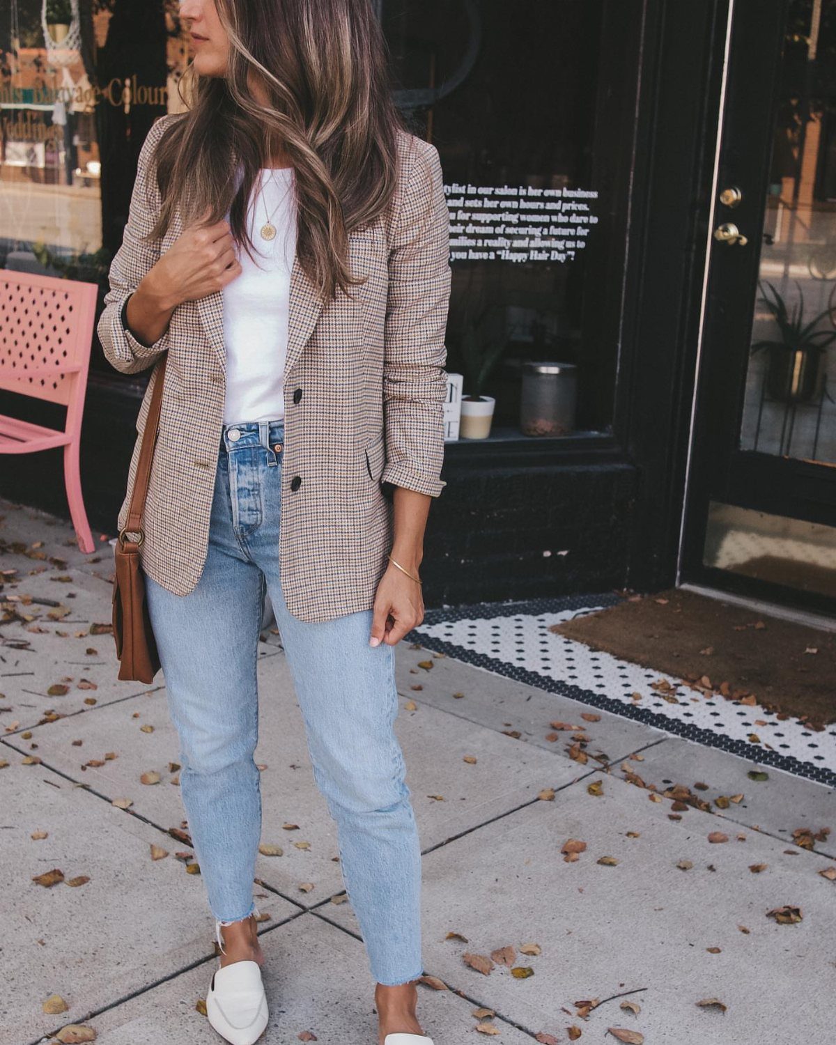 Woman wearing a checkered relaxed blazer, white t-shirt, and light blue jeans standing outdoors.