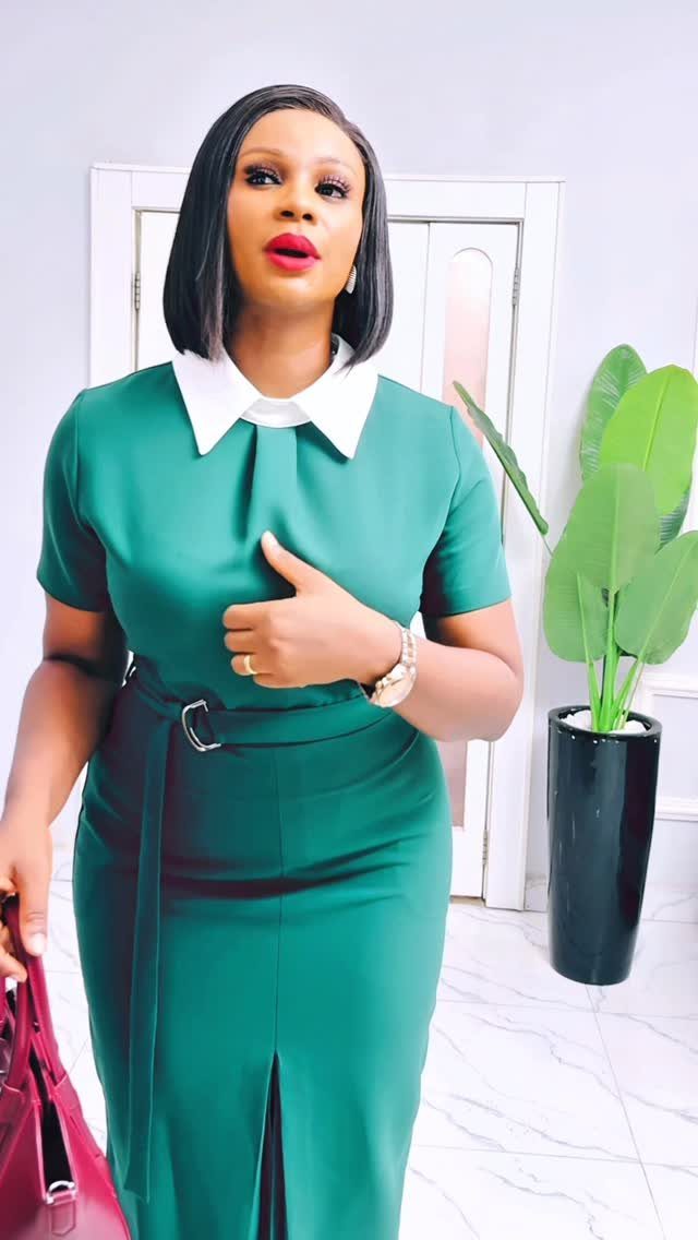 Woman wearing an emerald green midi-length sheath dress with a white collar and belt.