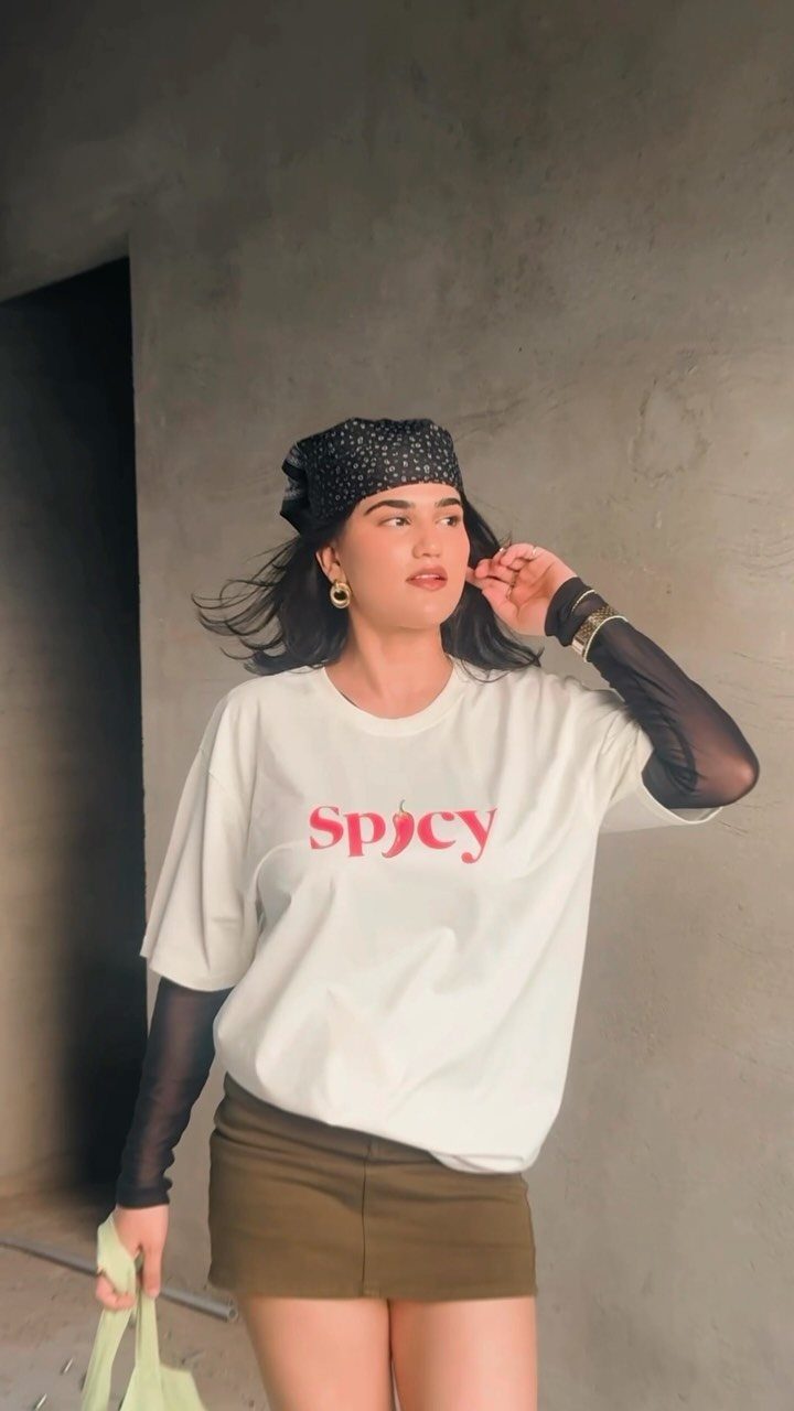 A woman wearing a white graphic t-shirt and an olive green mini skirt.