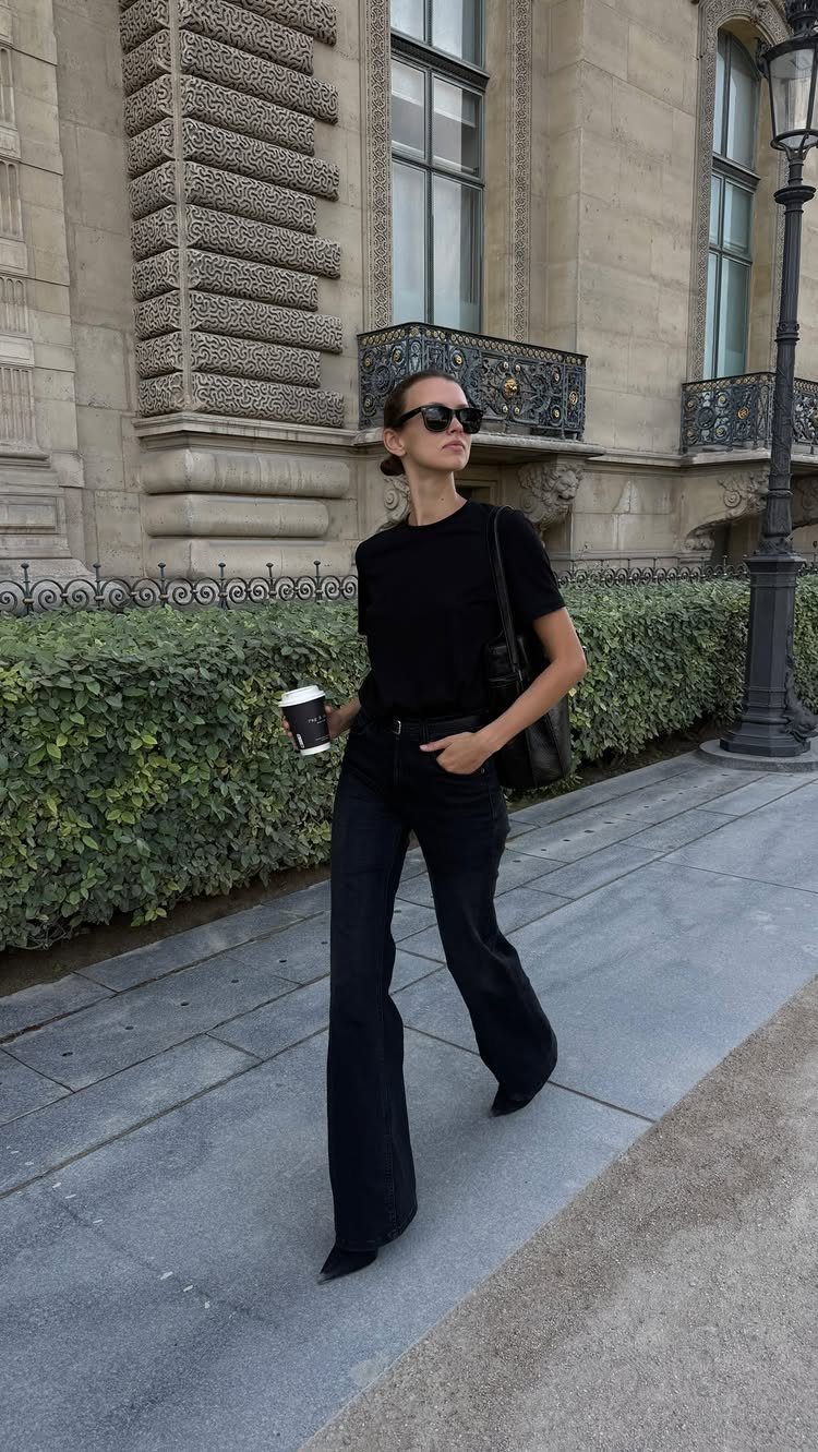 Woman in black flared jeans and high heels walking on a city sidewalk.