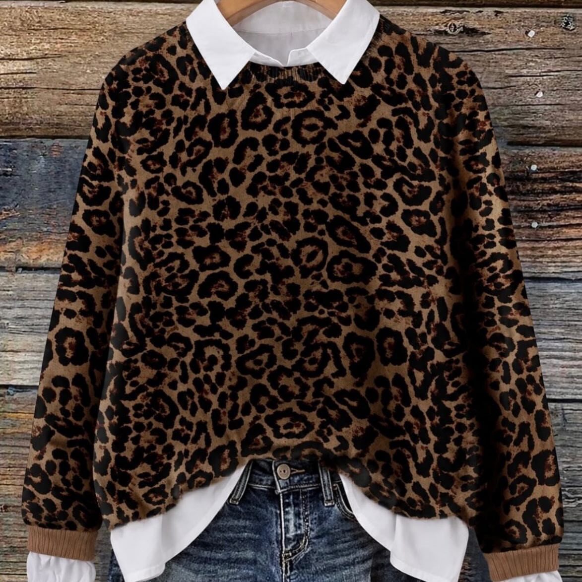 Leopard print sweater worn over a white collared shirt and blue denim jeans.