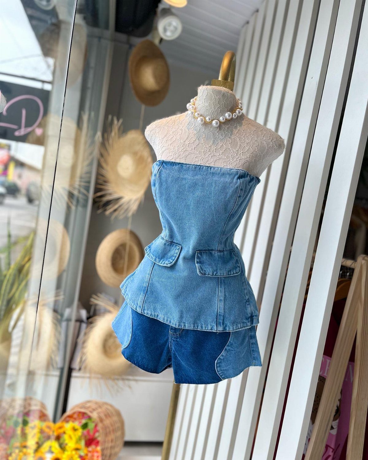 Denim corset top and matching shorts displayed on a mannequin with a pearl necklace.