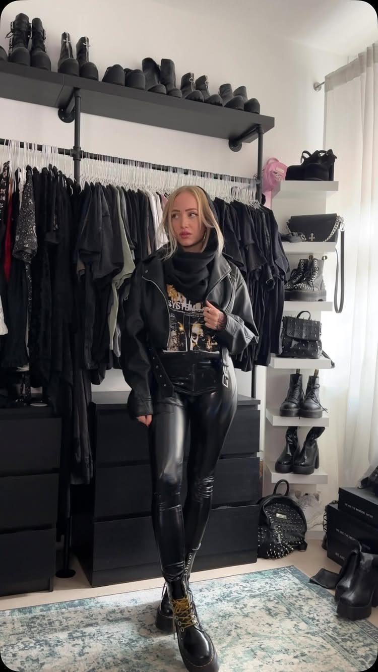Blonde woman wearing a black leather jacket, graphic t-shirt, and leather leggings in a closet.