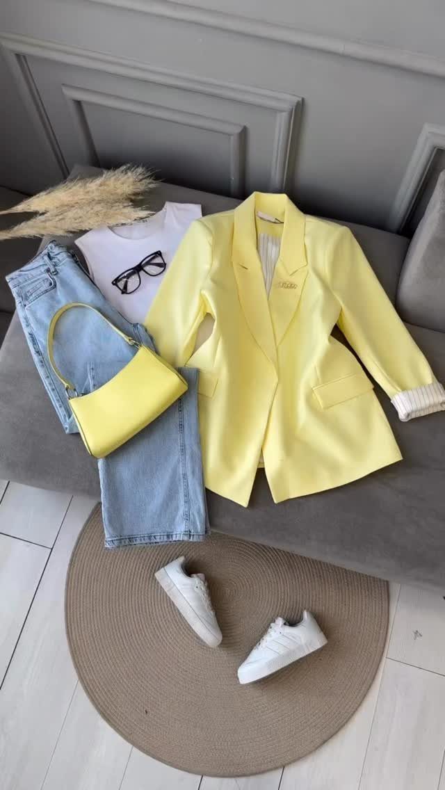 Yellow blazer, white t-shirt, light blue jeans, yellow handbag, and white sneakers arranged in a flat lay.