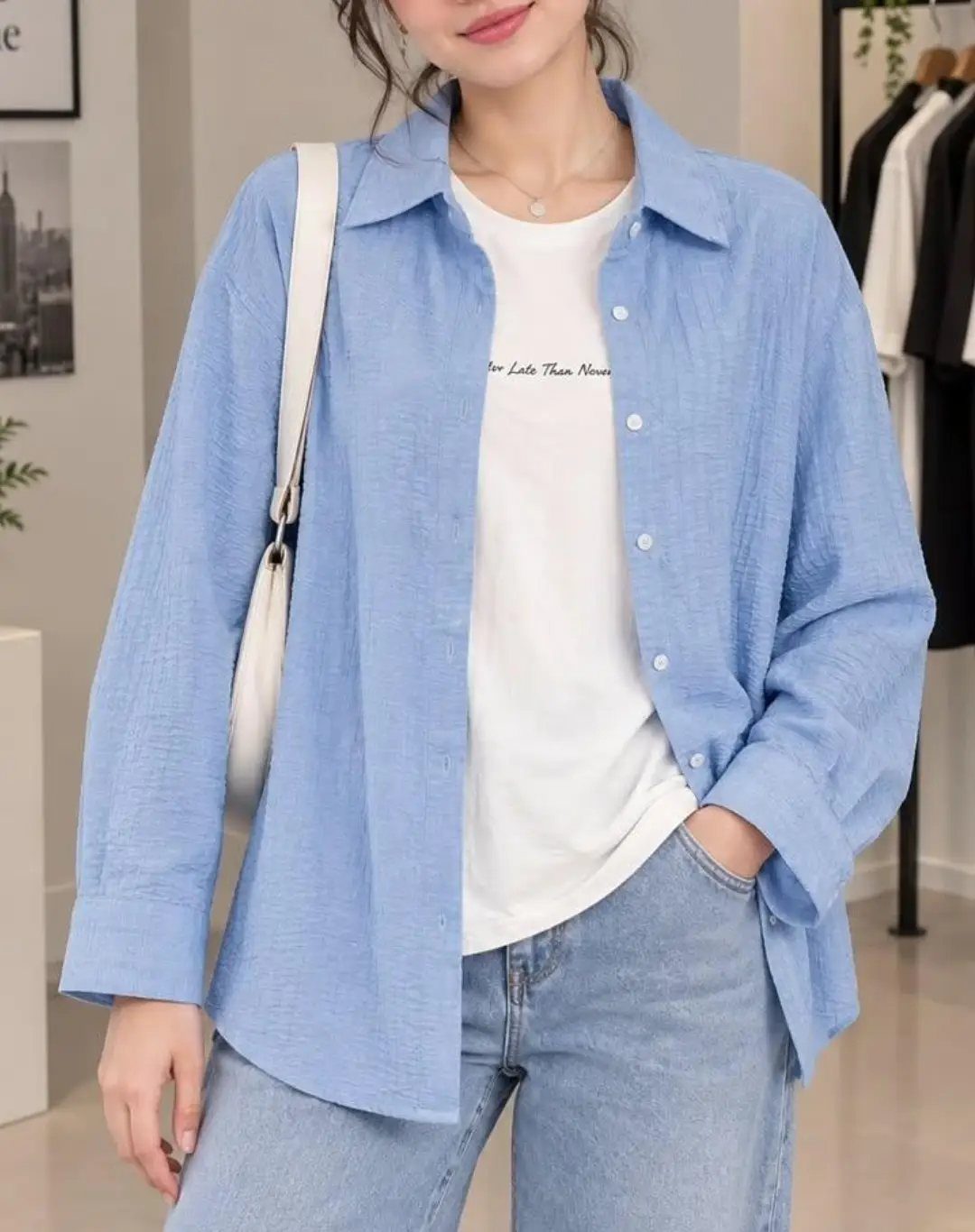 Woman wearing an open light blue linen shirt over a white t-shirt and light blue jeans.