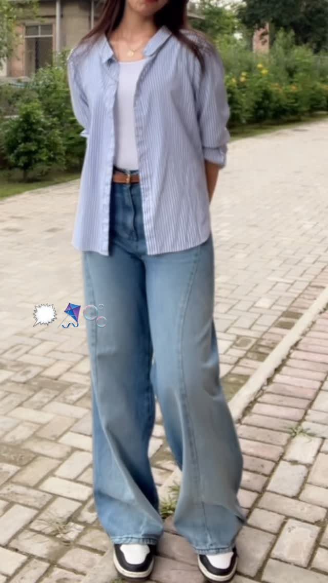 Person wearing a striped long-sleeve shirt, white top, and wide-leg light blue jeans.
