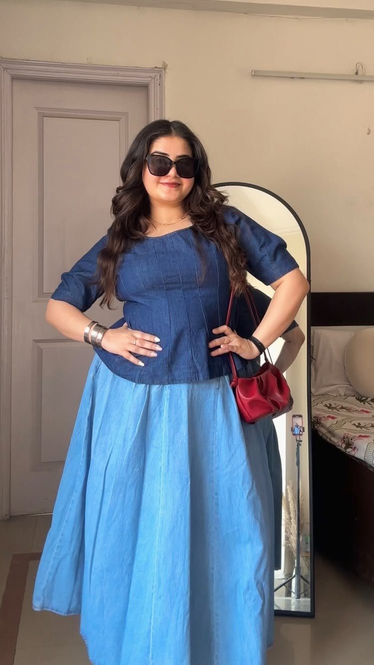 A woman posing in a blue top and a long, flowing light blue maxi skirt.