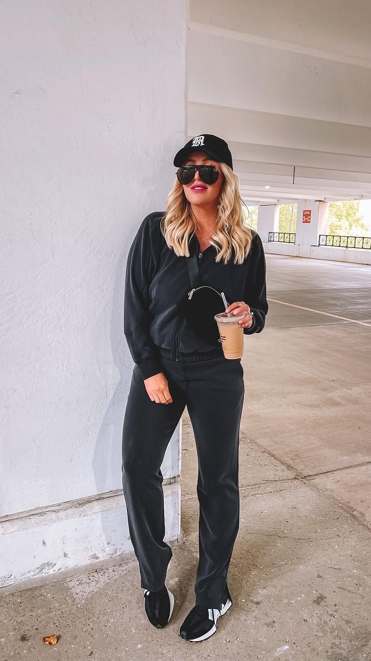 Woman in black wide-leg trousers and a matching top standing in a parking garage.