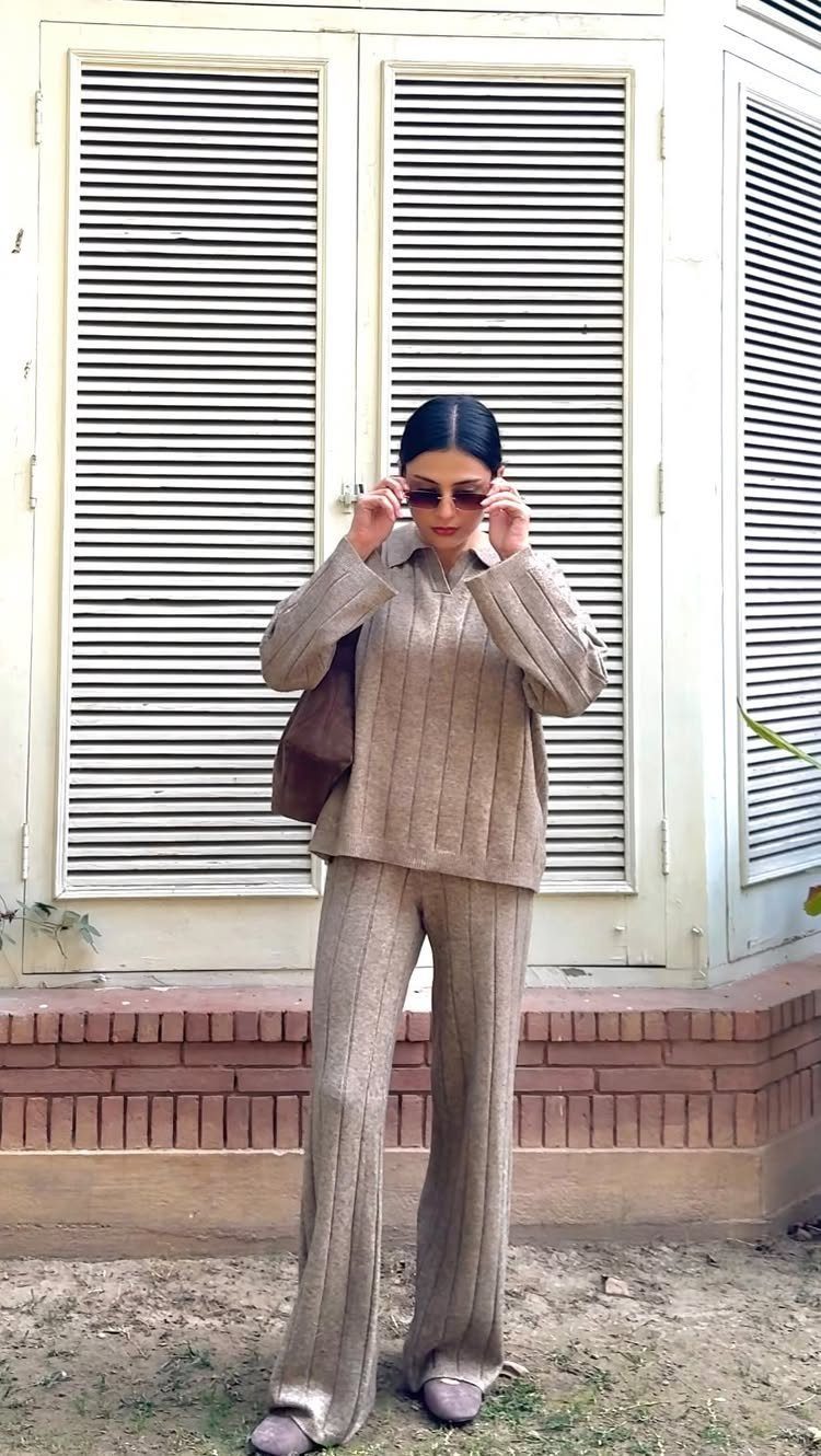 Woman wearing a matching beige ribbed knit sweater and wide-leg trousers standing outdoors.