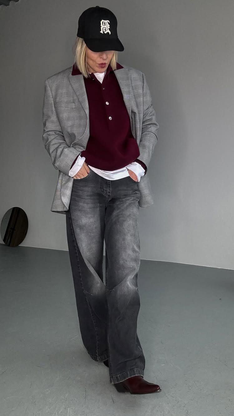 A woman wearing a grey blazer, maroon polo, white shirt, and wide-leg grey jeans.