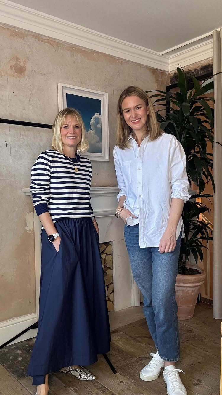 Two women posing indoors wearing stylish casual outfits consisting of stripes, denim, and white shirts.