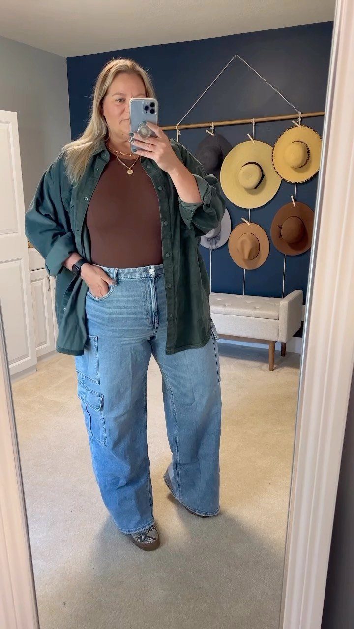 Woman in a mirror selfie wearing a brown top, green shirt, and wide-leg denim jeans.