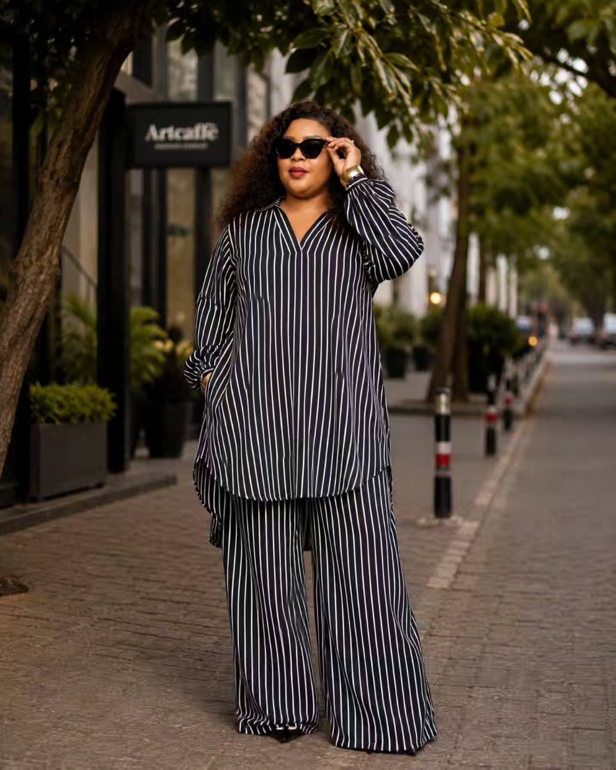 A woman wearing a navy and white vertical striped tunic and matching wide-leg trousers standing outdoors.