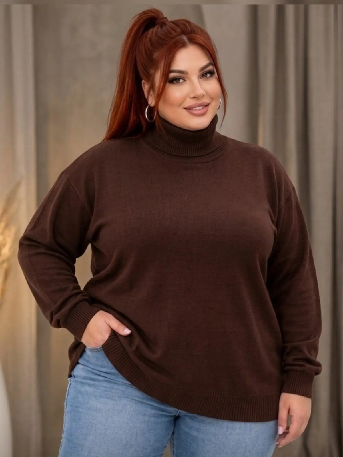 A woman with red hair wearing a dark brown turtleneck sweater and blue jeans.