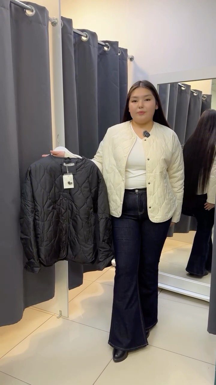A woman wearing dark wash flared denim jeans and a white top in a fitting room.