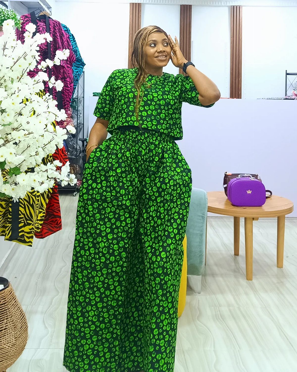 A woman posing in a green and black patterned high-waisted wide-leg trouser set.