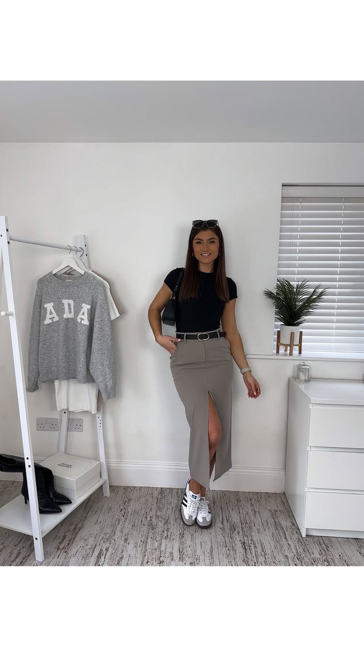 Woman wearing a black top and a tan midi skirt with a front slit.