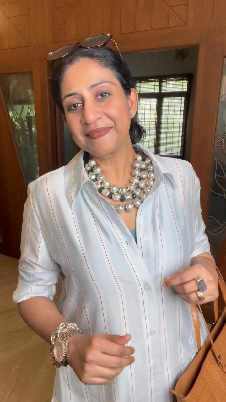 A woman wearing a striped shirt and a large, chunky silver beaded necklace.