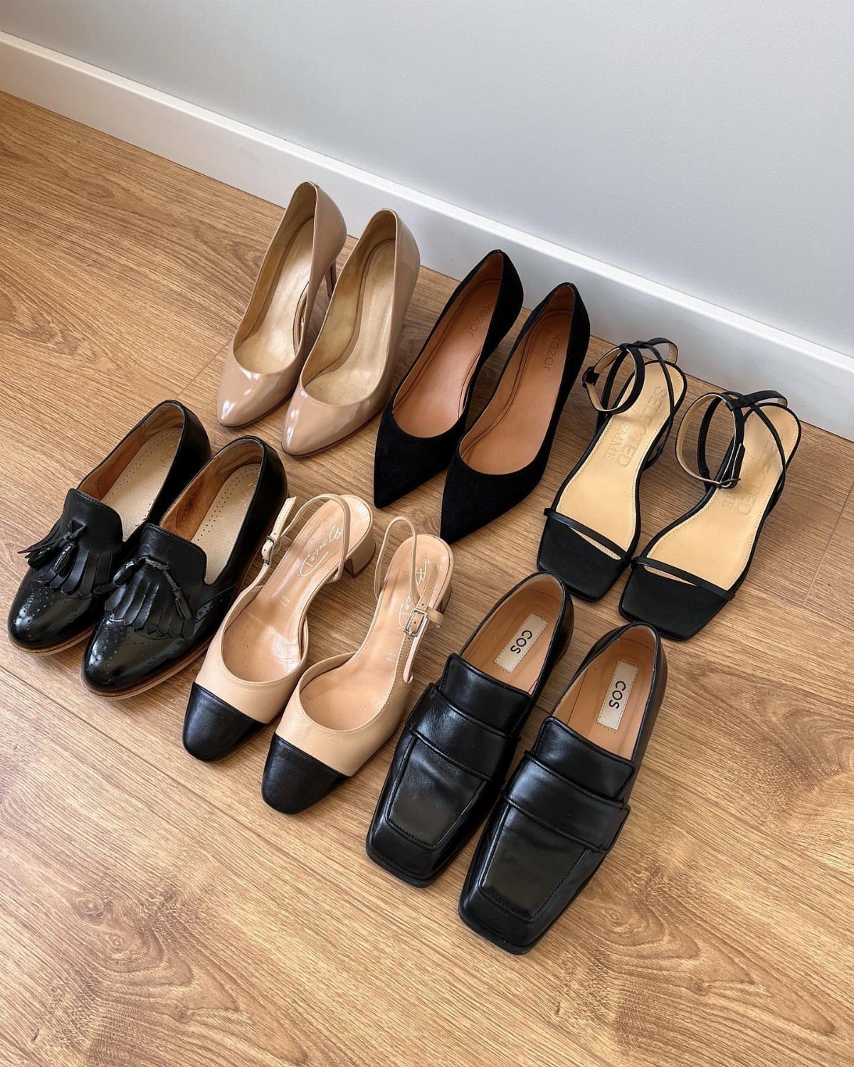 Various pairs of stylish women's office shoes arranged on a wooden floor.