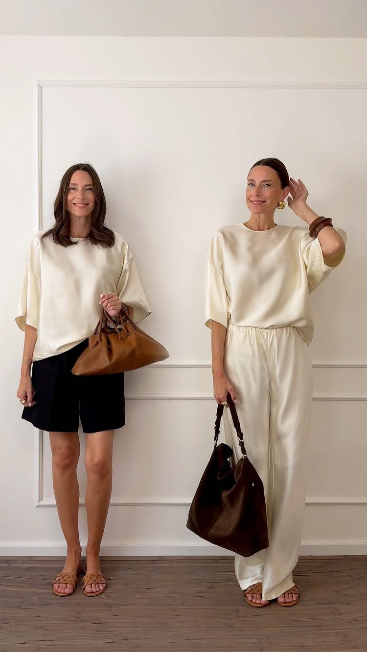 Two women posing in cream tops with black shorts and white wide-leg pants.