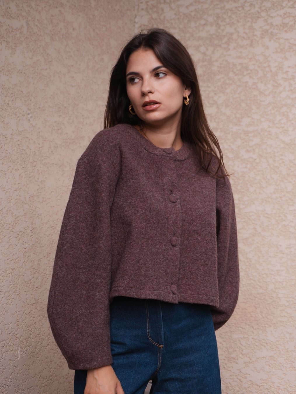 Woman wearing a cropped brown button-up sweater and high-waisted blue jeans.