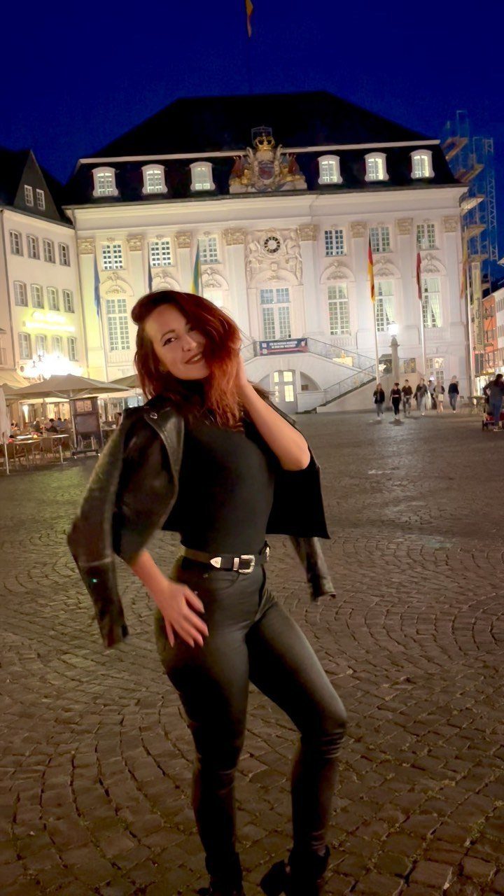 Woman posing in a city square wearing a black turtleneck and black leather pants.