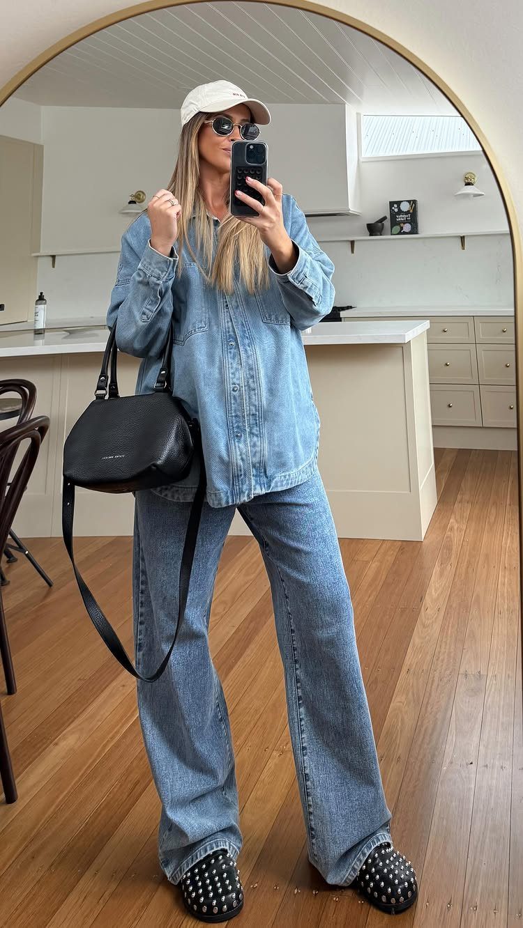 Woman in a denim shirt and wide leg jeans posing for a mirror selfie.