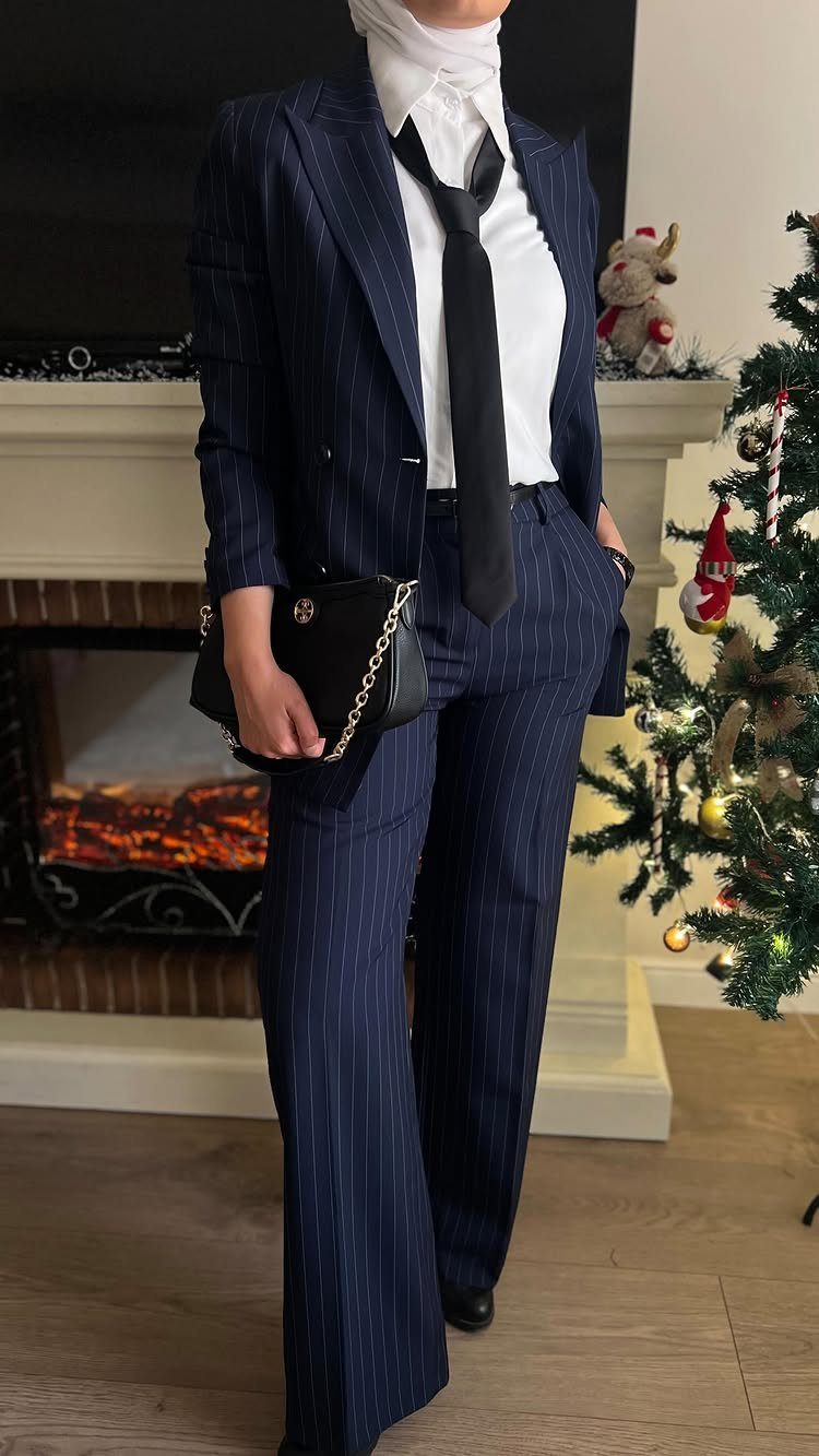 A person wearing a navy blue pinstripe suit with a white shirt and black tie.