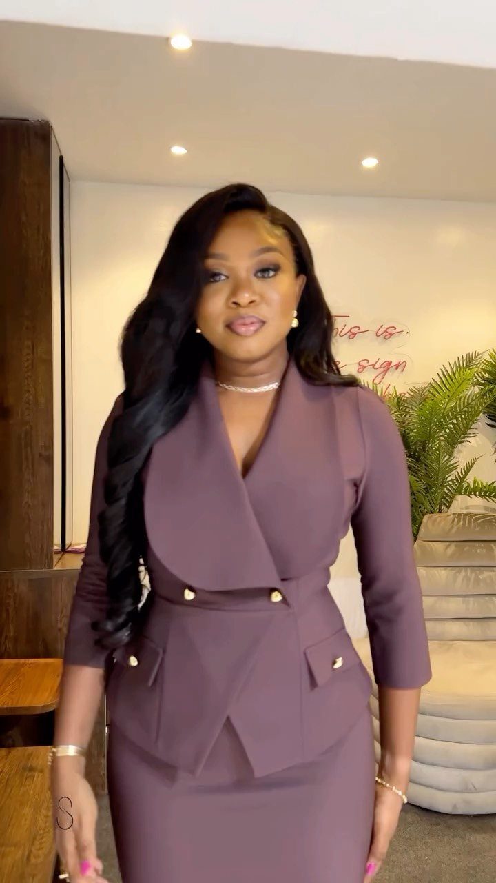 A woman posing in a mauve tailored blazer and matching skirt set.