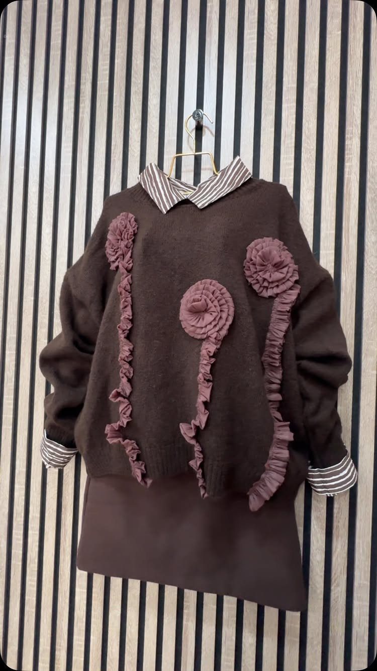 Brown sweater with mauve floral ruffles layered over a striped shirt and paired with a brown skirt.